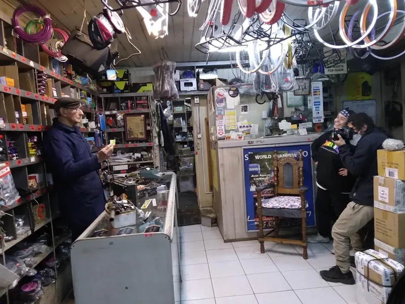 Gumercindo Díaz en su taller de bicicletas de Temuco durante el rodaje; integrantes del equipo registran la escena, septiembre de 2021.
